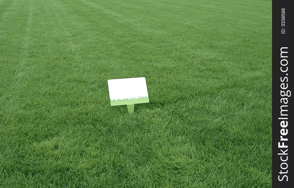 Fresh green grass background with a white sign ready to write