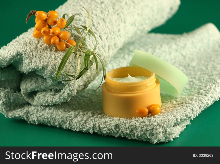 Branch of sea-buckthorn berries, a cream and a towel. Branch of sea-buckthorn berries, a cream and a towel.