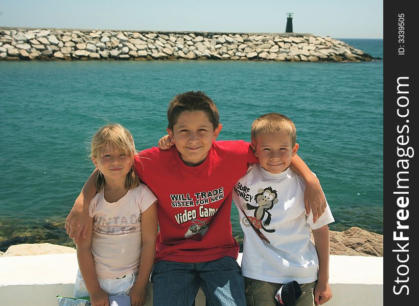 Three siblings all sat on a wall with a the port entrance to Puerto Duquesa behind them. Three siblings all sat on a wall with a the port entrance to Puerto Duquesa behind them