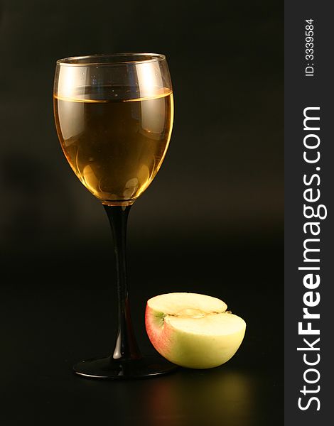 Glass of white wine and an apple on a black background. Glass of white wine and an apple on a black background