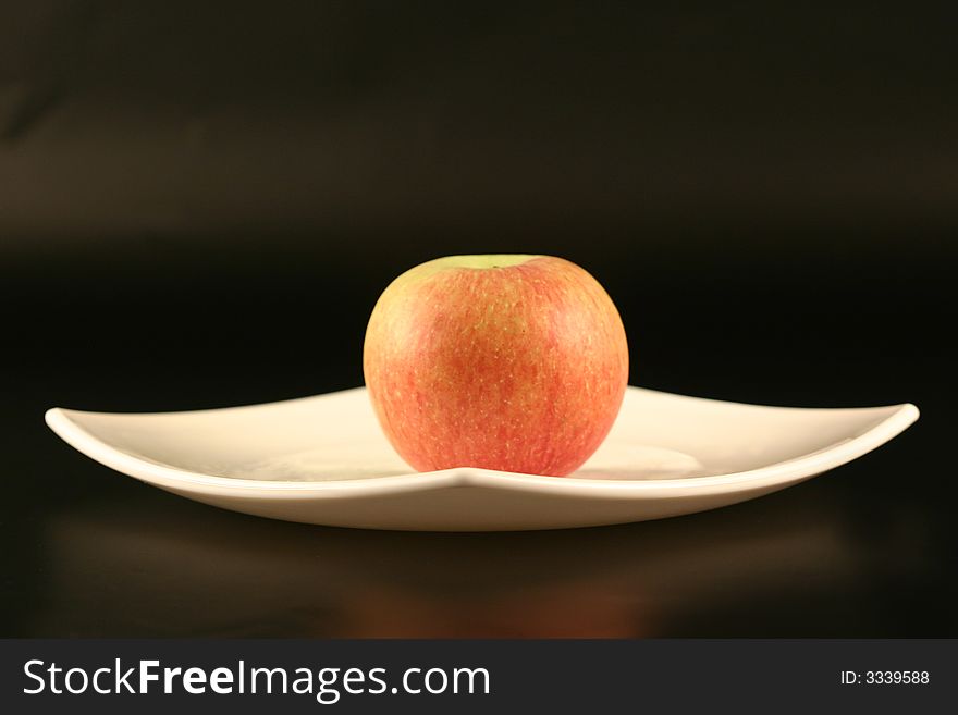 Plate with an apple on a black background