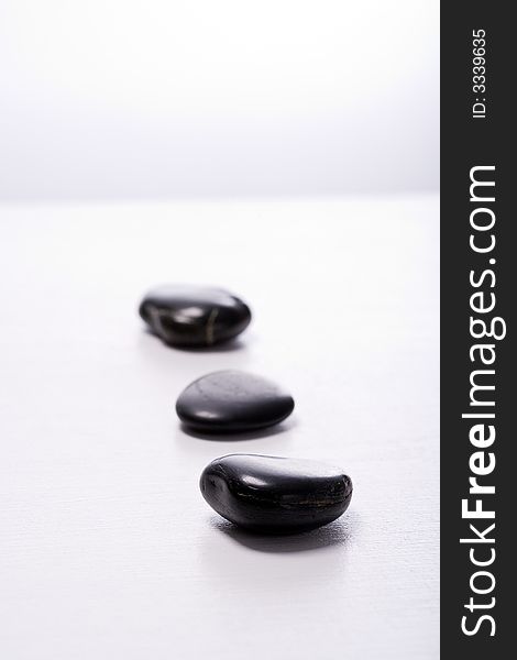 Three smooth, black Zen-Stones (Pebbles) in a row. Focus on front stone. Three smooth, black Zen-Stones (Pebbles) in a row. Focus on front stone.