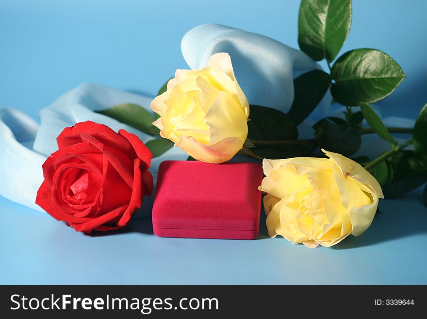 Roses and a box with a gold ring on a blue background.