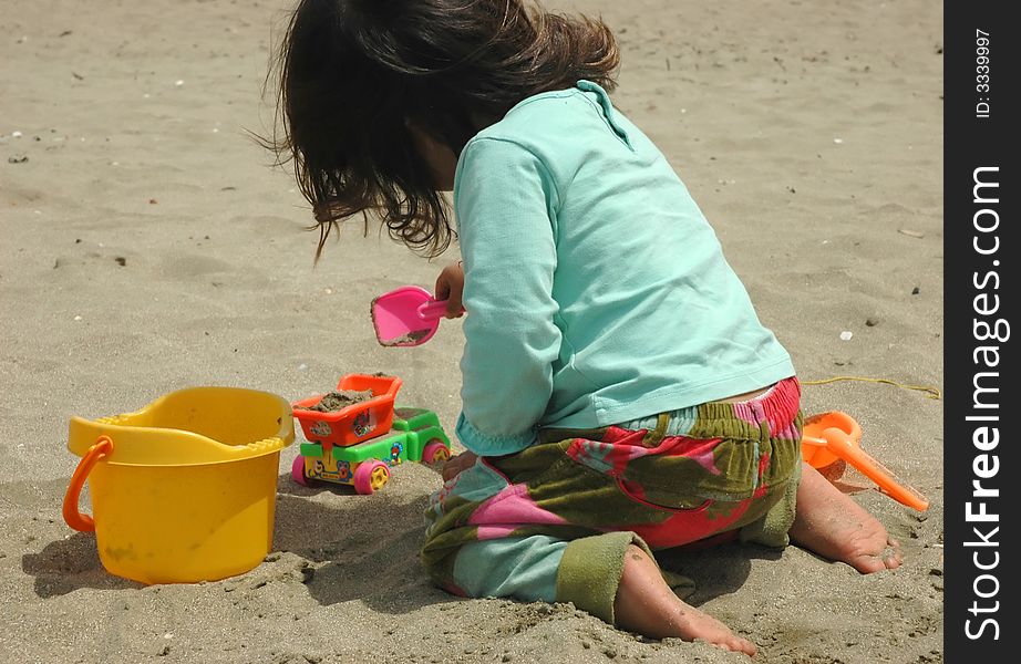 Little girl, sand and toys