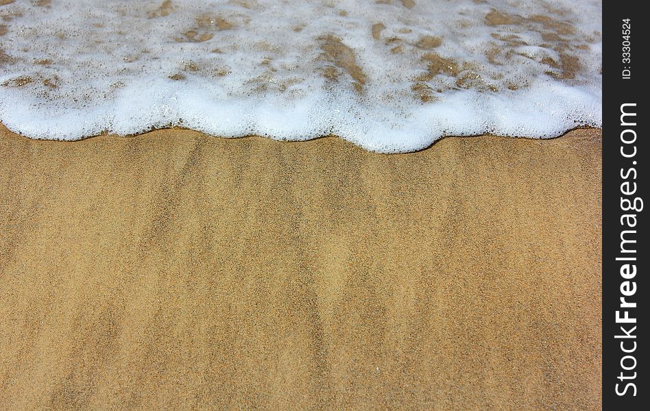 Sea â€‹â€‹waves and wet sand on the beach as summer background