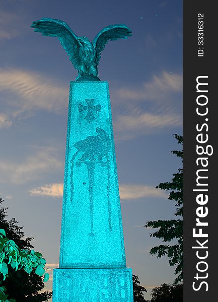 A monument consisting of a column of stone with an eagle of bronze on top of it, remainding of the deads of the world war 1914-1918, taken with cyan light. A monument consisting of a column of stone with an eagle of bronze on top of it, remainding of the deads of the world war 1914-1918, taken with cyan light