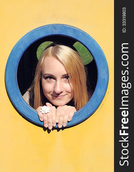 The young girl looks through a window on a playground