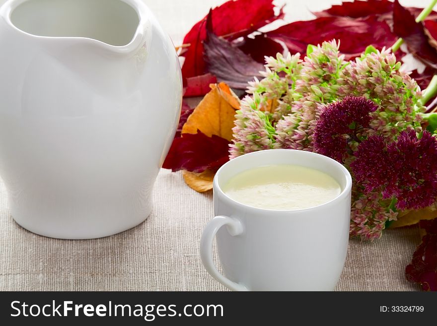 A cup of milk milk jug autumn leaves and flowers. A cup of milk milk jug autumn leaves and flowers