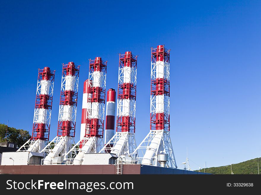 Power plant pipes against the blue sky in the bright sunny day