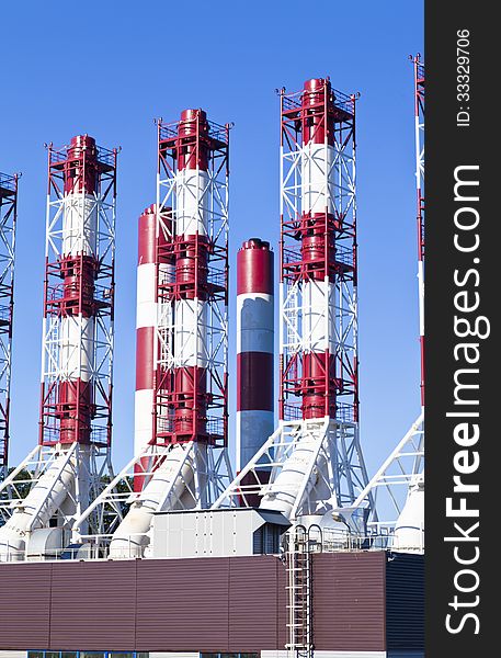 Power plant pipes against the blue sky in the bright sunny day