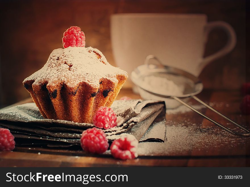 Fruitcake Decorated with Raspberry and icing sugar at the wooden table, tonal
