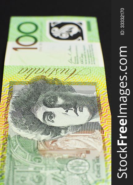 Australian green and gold 100 hundred dollar note, against a black background. vertical. Australian green and gold 100 hundred dollar note, against a black background. vertical.