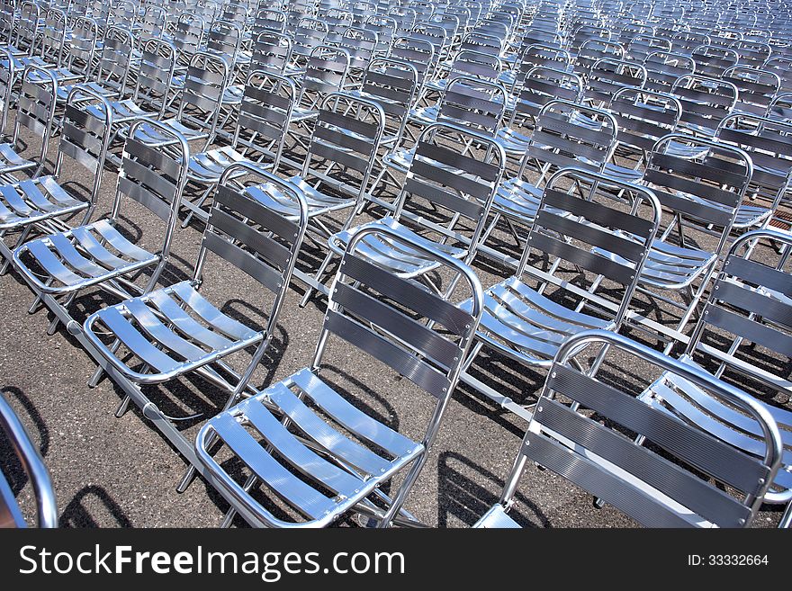 Lot of empty metal seats in a row outdoors under sun light. Lot of empty metal seats in a row outdoors under sun light