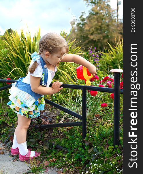 Portrait little girl watering the grass