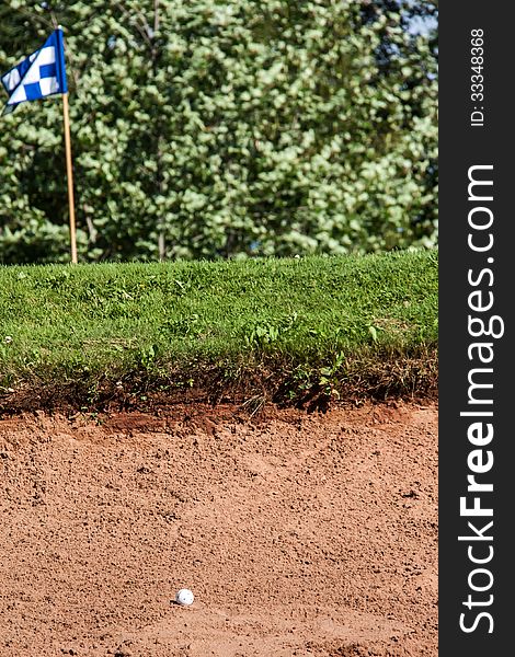 White golf ball on the edge of a sand hazard. White golf ball on the edge of a sand hazard