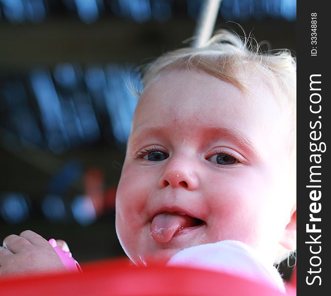 Blonde blue eyed baby girl with tongue out. Blonde blue eyed baby girl with tongue out