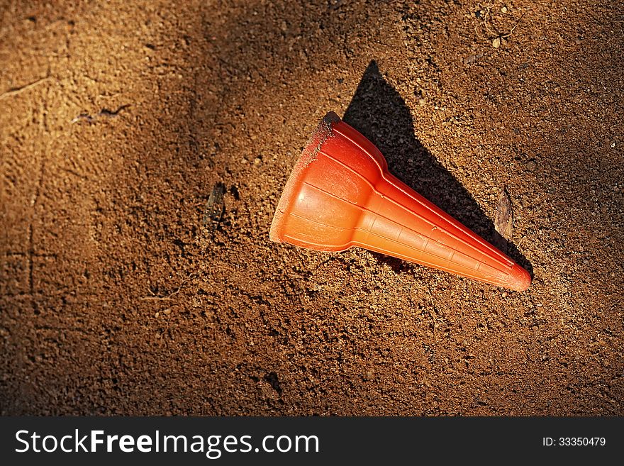 A plastic ice-cream cone with an orange colour was lost in the sandpit. A plastic ice-cream cone with an orange colour was lost in the sandpit