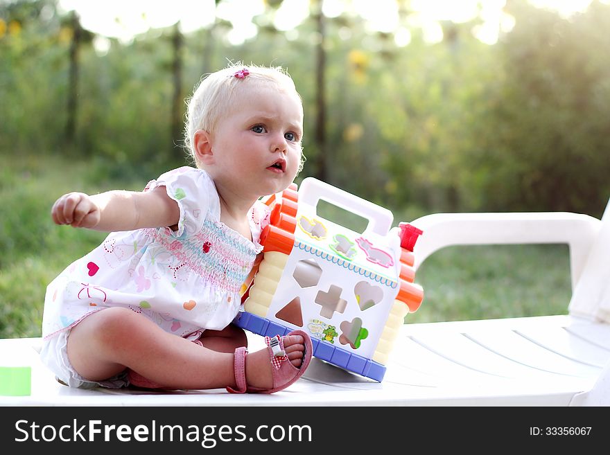 Blonde blue eyed baby girl with a toy. Blonde blue eyed baby girl with a toy