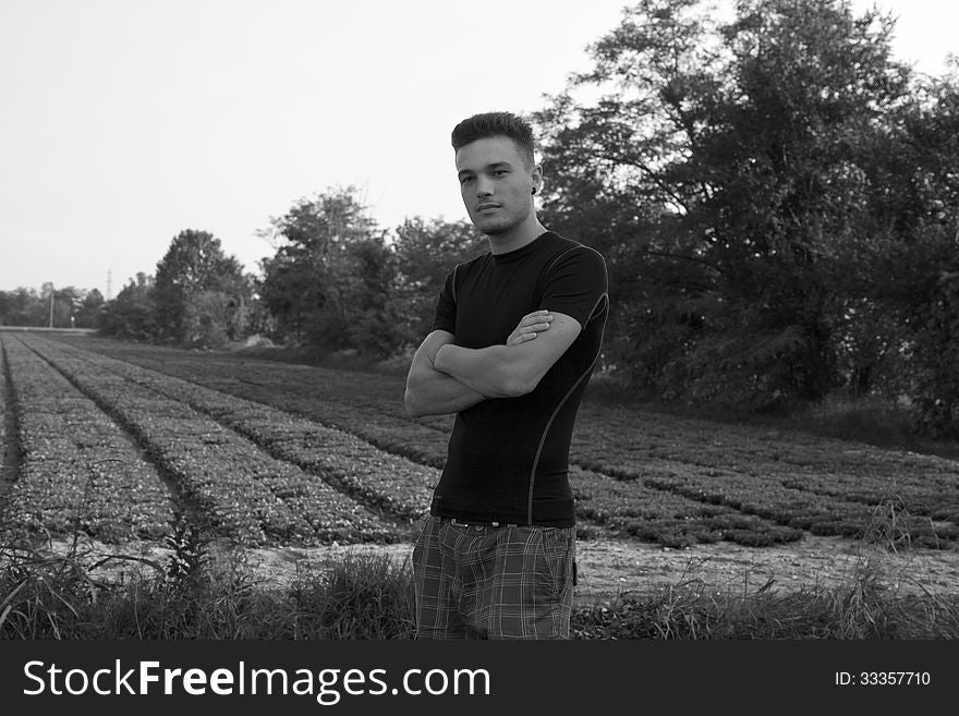Handsome guy standing near a field, in black & white