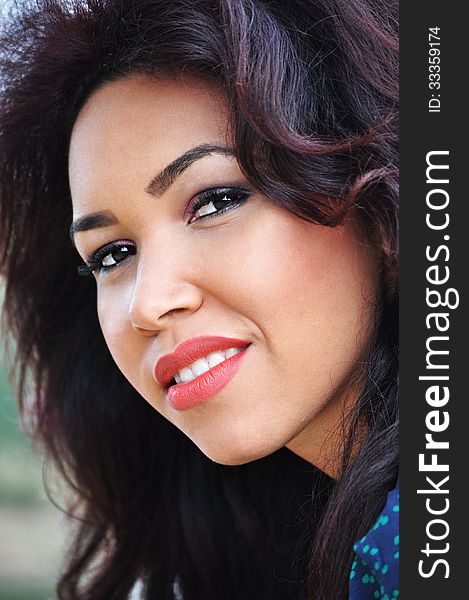 Outdoor portrait of an attractive young woman with long blac hair.