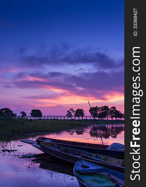 Docked boat on swamp field at dawn with beautiful vivid sky