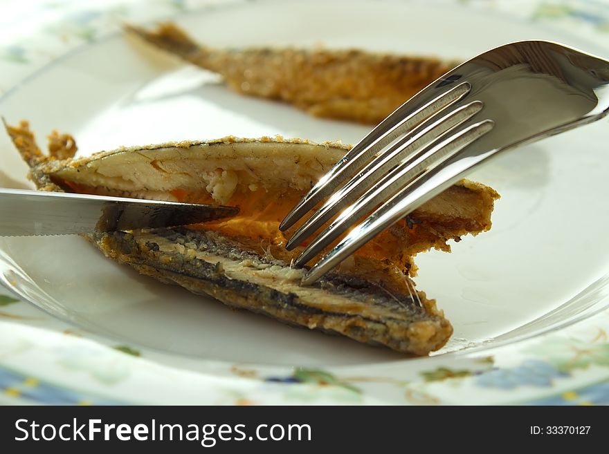 Cleaning cooked fish (fried vendace, small freshwater whitefish) for eating with fork and knife