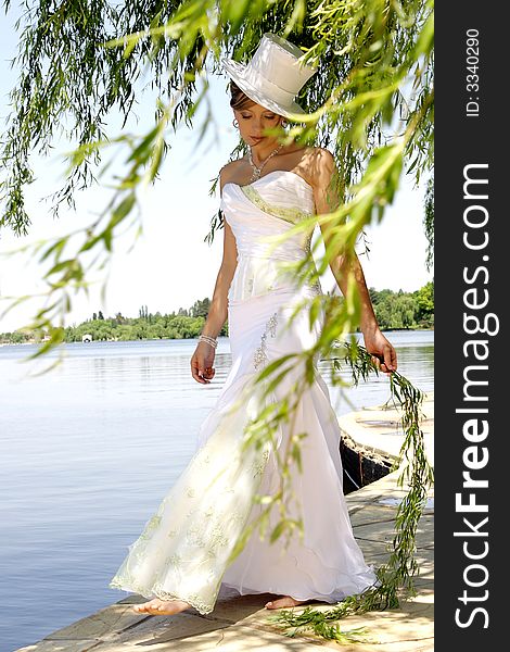 A bride standing between tree branches in her dress. A bride standing between tree branches in her dress