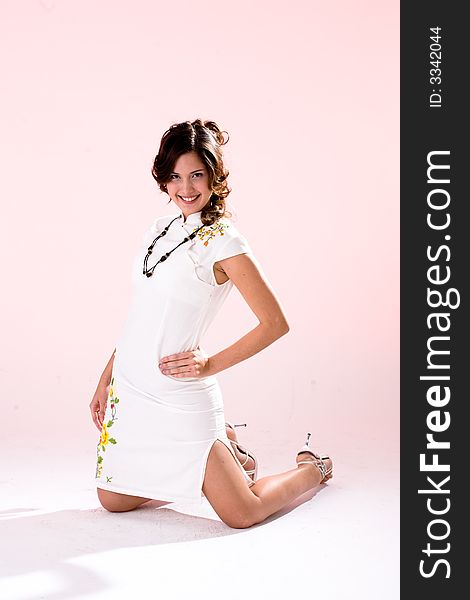 Young multi-racial woman with a beautiful smile kneeling wearing a white dress. Young multi-racial woman with a beautiful smile kneeling wearing a white dress