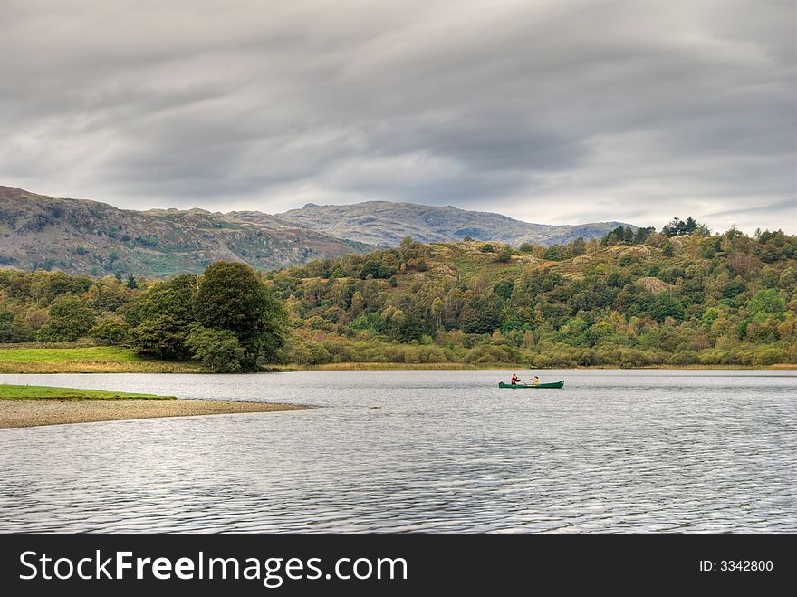 Two people canoeing on Rydal Water in the English Lake District under an overcast sky. Two people canoeing on Rydal Water in the English Lake District under an overcast sky