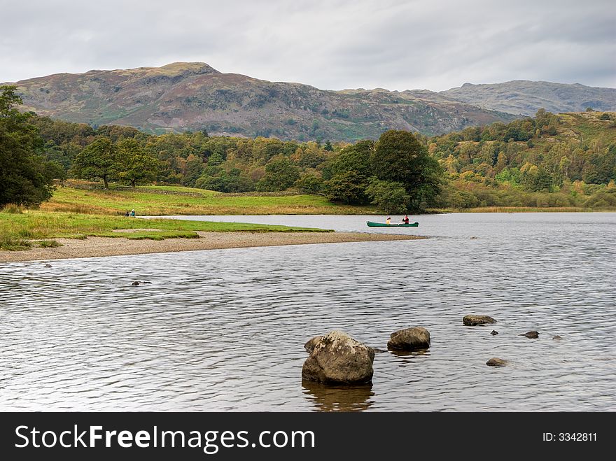 Two people canoeing on Rydal Water in the English Lake District under an overcast sky. Two people canoeing on Rydal Water in the English Lake District under an overcast sky