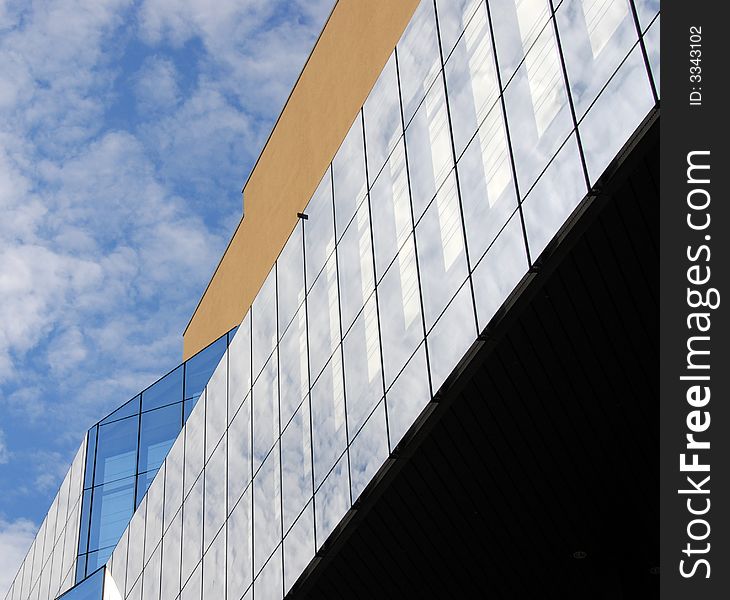 Modern building with glass windows and a modern design agains a cloudy  sky