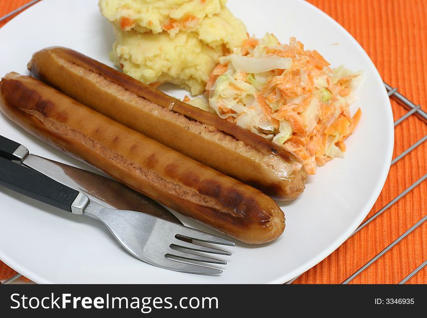 Pan grilled jumbo frankfurters with side serving of mash and coleslaw