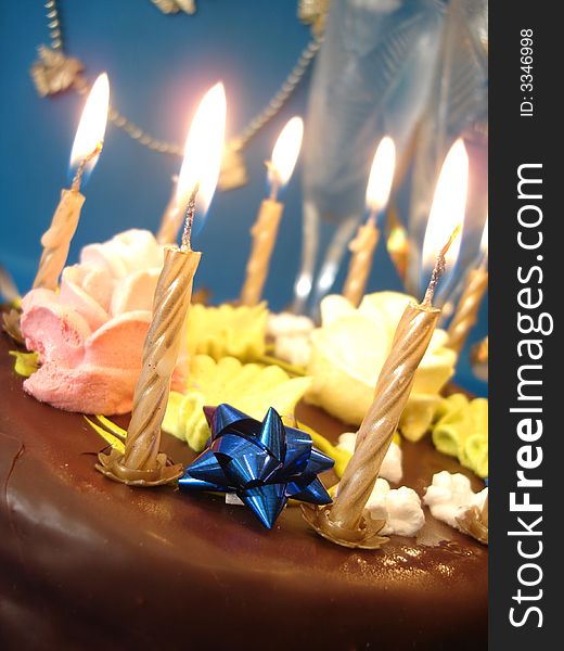 Cake and candles, two glasses with champagne on blue