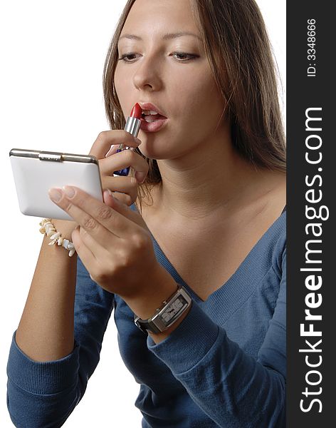 Girl in the blue blouse is painting lips with the red lipstick on the white background. Girl in the blue blouse is painting lips with the red lipstick on the white background