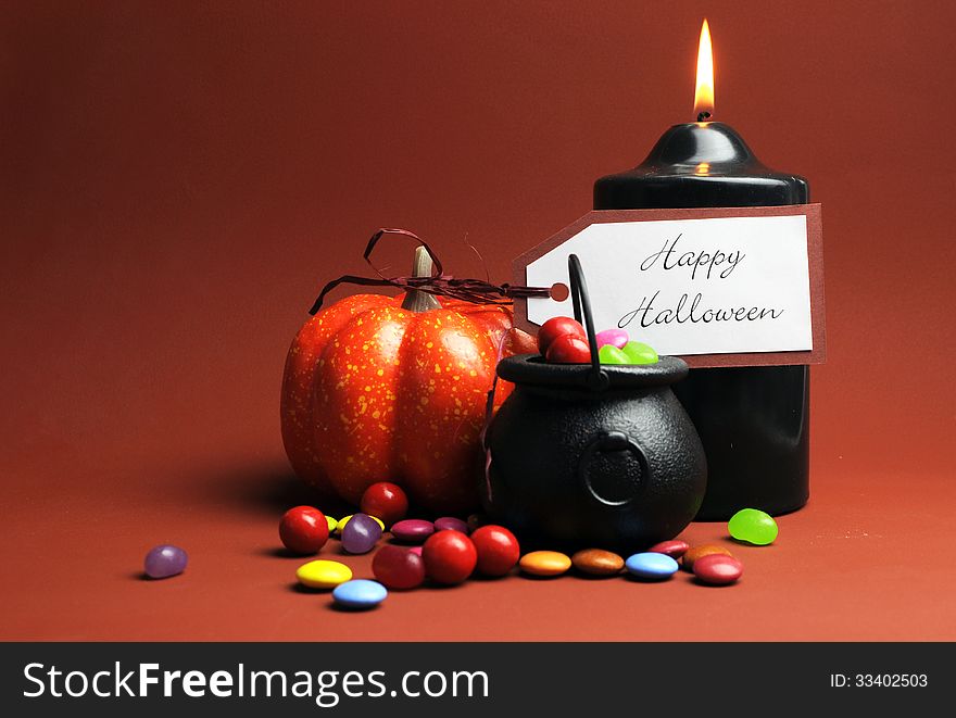 Row of Halloween Trick or Treat witches cauldrons full of candy on autumn brown background with black candle and orange pumpkin. Row of Halloween Trick or Treat witches cauldrons full of candy on autumn brown background with black candle and orange pumpkin.