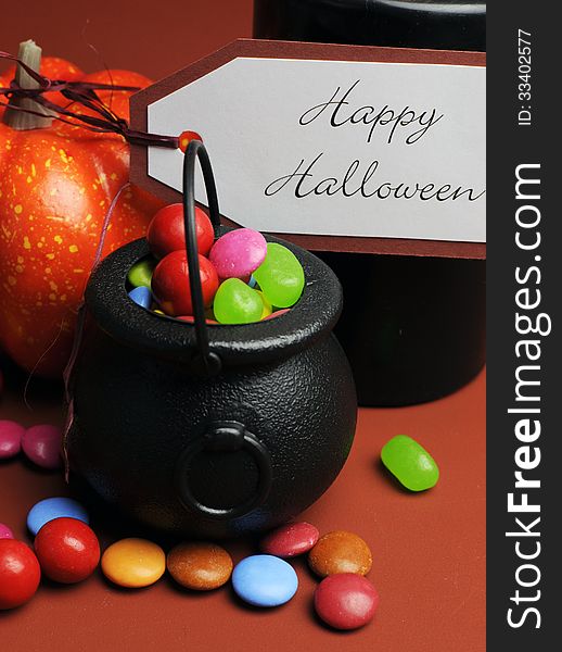 Row of Halloween Trick or Treat witches cauldrons full of candy on autumn brown background with black candle and orange pumpkin. Row of Halloween Trick or Treat witches cauldrons full of candy on autumn brown background with black candle and orange pumpkin.