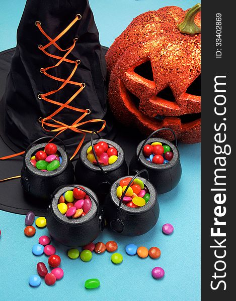 Halloween black witch hat and cauldrons full of candy with pumpkin jack o lantern for trick or treating. Vertical. Halloween black witch hat and cauldrons full of candy with pumpkin jack o lantern for trick or treating. Vertical.