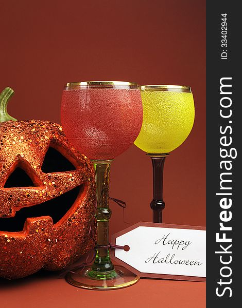 Halloween drinks with vintage gothic style red, yellow and green wine goblet glasses and orange Jack o Lantern pumpkin decoration. Halloween drinks with vintage gothic style red, yellow and green wine goblet glasses and orange Jack o Lantern pumpkin decoration.