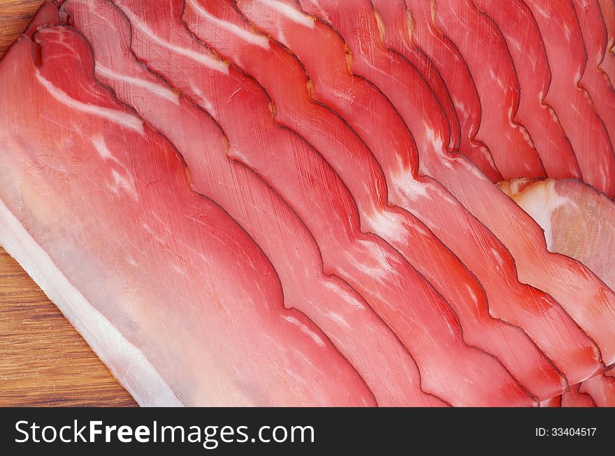 Slices of Delicious Smoked Pork In a Row closeup on Wooden Background. Slices of Delicious Smoked Pork In a Row closeup on Wooden Background