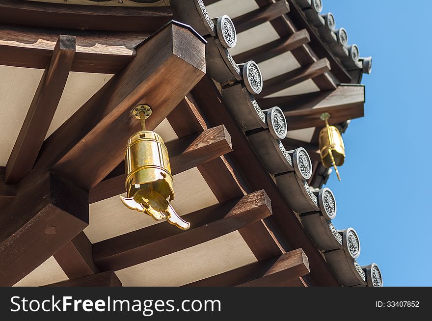 Close-Up view of underside of Japanese Pagoda Roof with Bells, Wooden Beams and Grey Tiles. Close-Up view of underside of Japanese Pagoda Roof with Bells, Wooden Beams and Grey Tiles