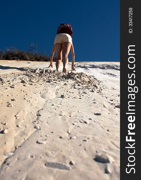 A woman climbs the dune in rainbow beach, queensland, australia. A woman climbs the dune in rainbow beach, queensland, australia