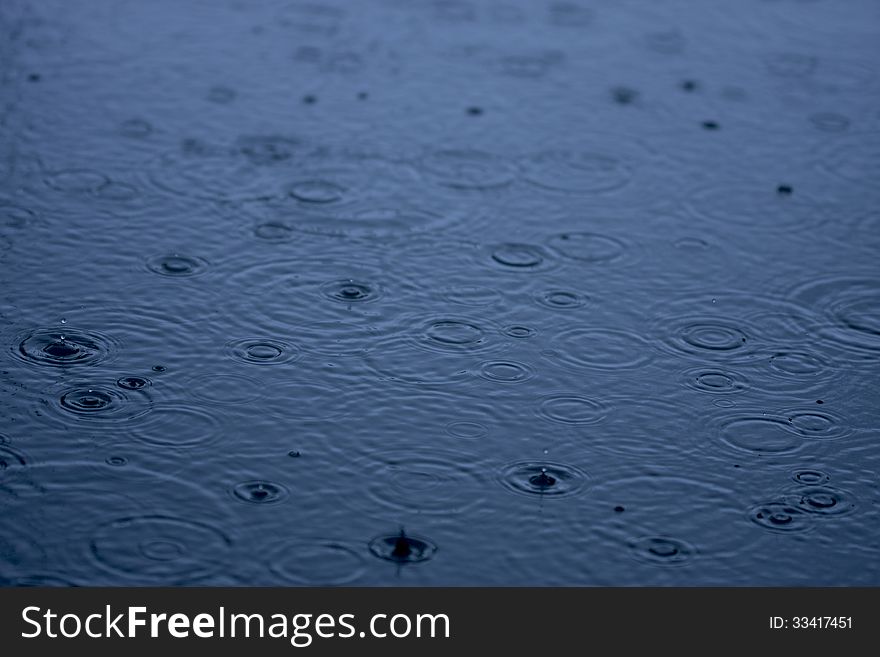 Raindrops on a blue surface of the water