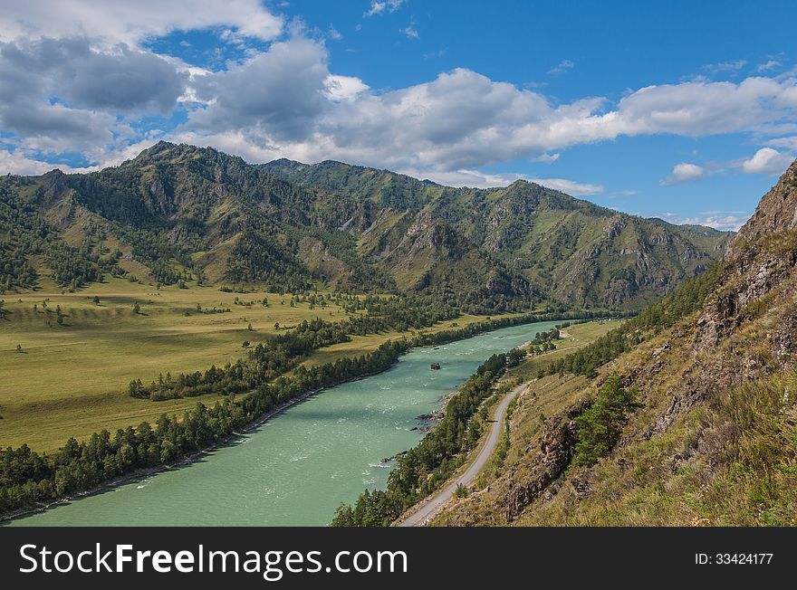Mountain landscape with turquoise river, trees along the banks, fields, road. View from the mountain. Mountain landscape with turquoise river, trees along the banks, fields, road. View from the mountain.