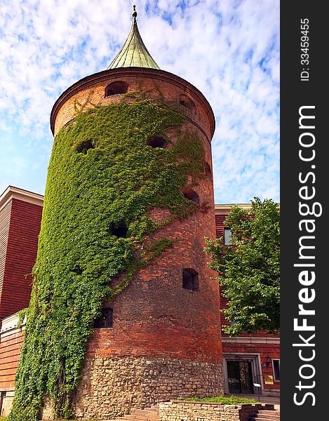 Antique powder tower of red brick green entwined with ivy