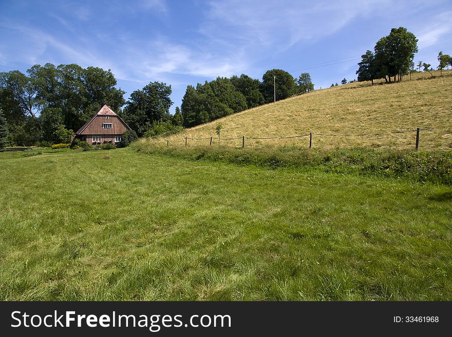 Brown wooden cottage in a green field