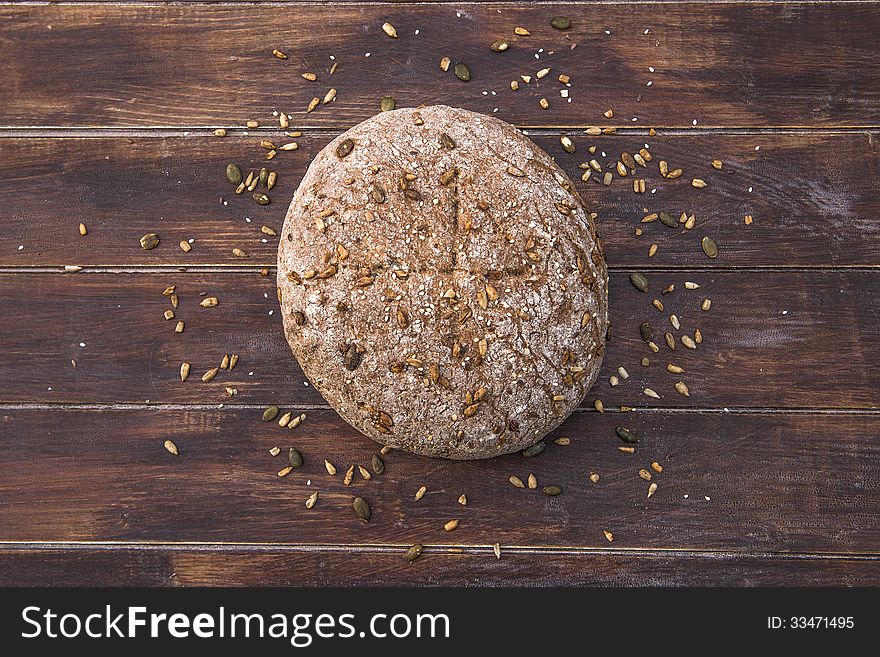 Home baked wholemeal bread with seeds scattered around it on wooden table. Home baked wholemeal bread with seeds scattered around it on wooden table