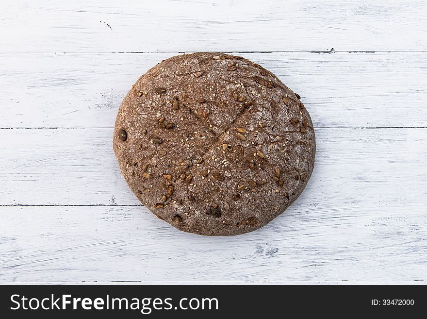 A loaf of wholemeal home baked bread on white board