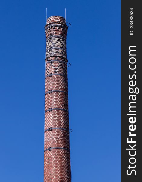Old and beautiful chimney of brewary, against blue sky. Old and beautiful chimney of brewary, against blue sky.