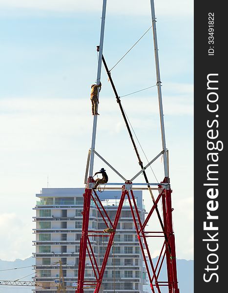 Two workers install a lot of Metal tiered tower.