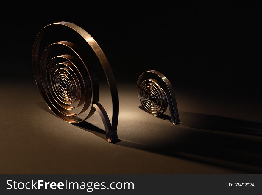 Pair of metal springs on dark background under beam of light